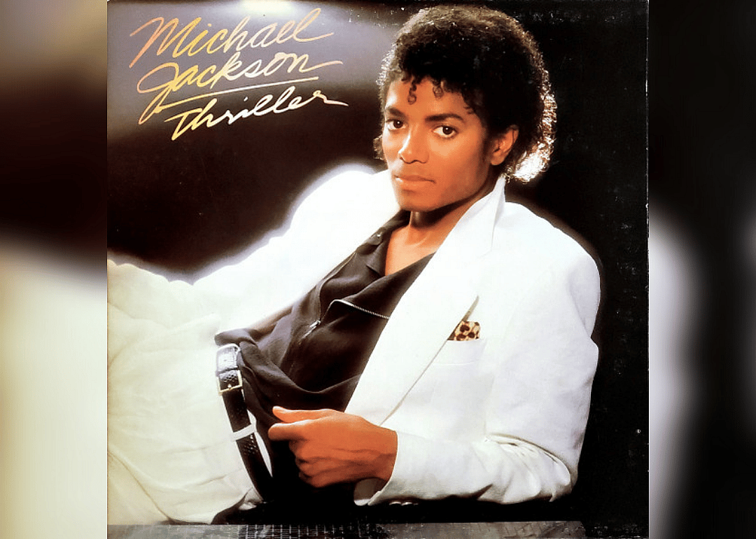 Michael Jackson posing on the ground with a white suit jacket on.