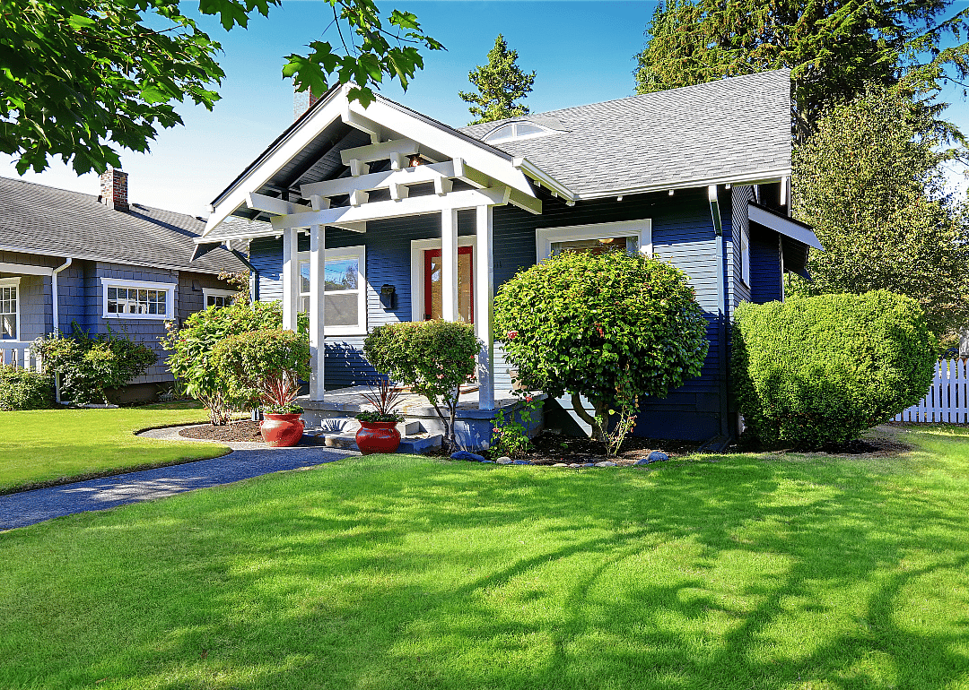 A small blue house with white trim and a green lawn.