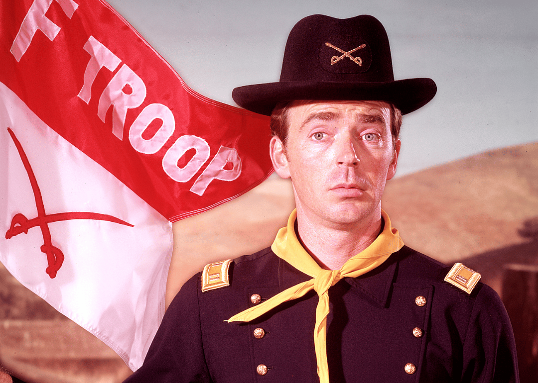 A man in a military uniform holding an F Troop flag.