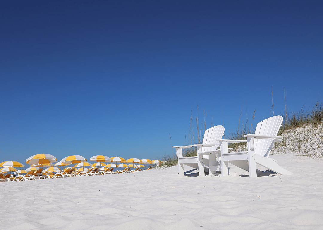Beach chairs and yellow umbrellas on a white sandy beach.