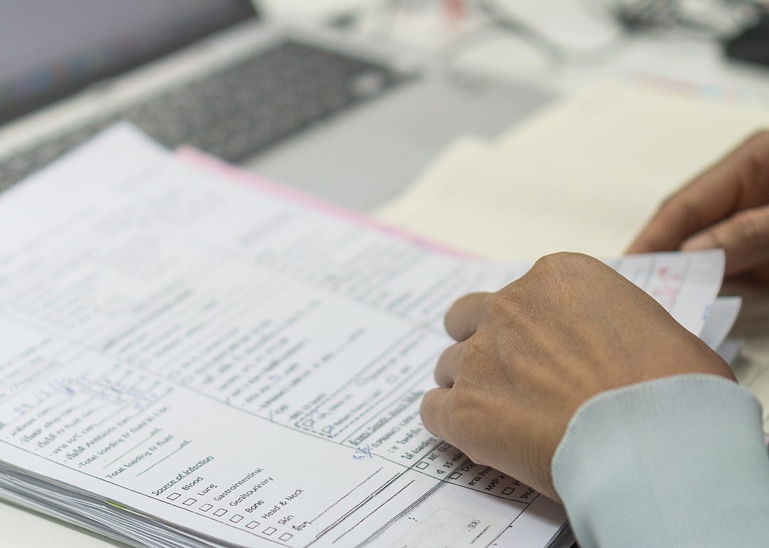 Hands flipping through printed medical records.