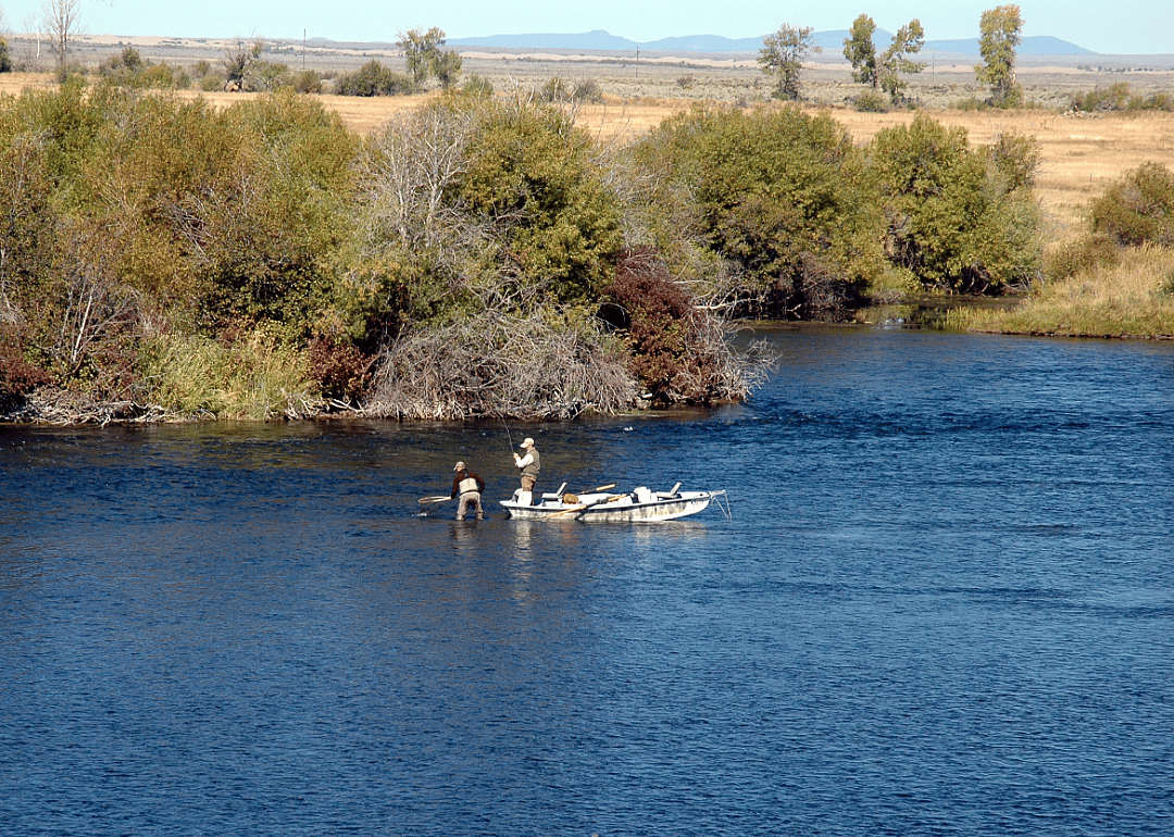 A couple of people on a small fishing boat on a calm lake. 
