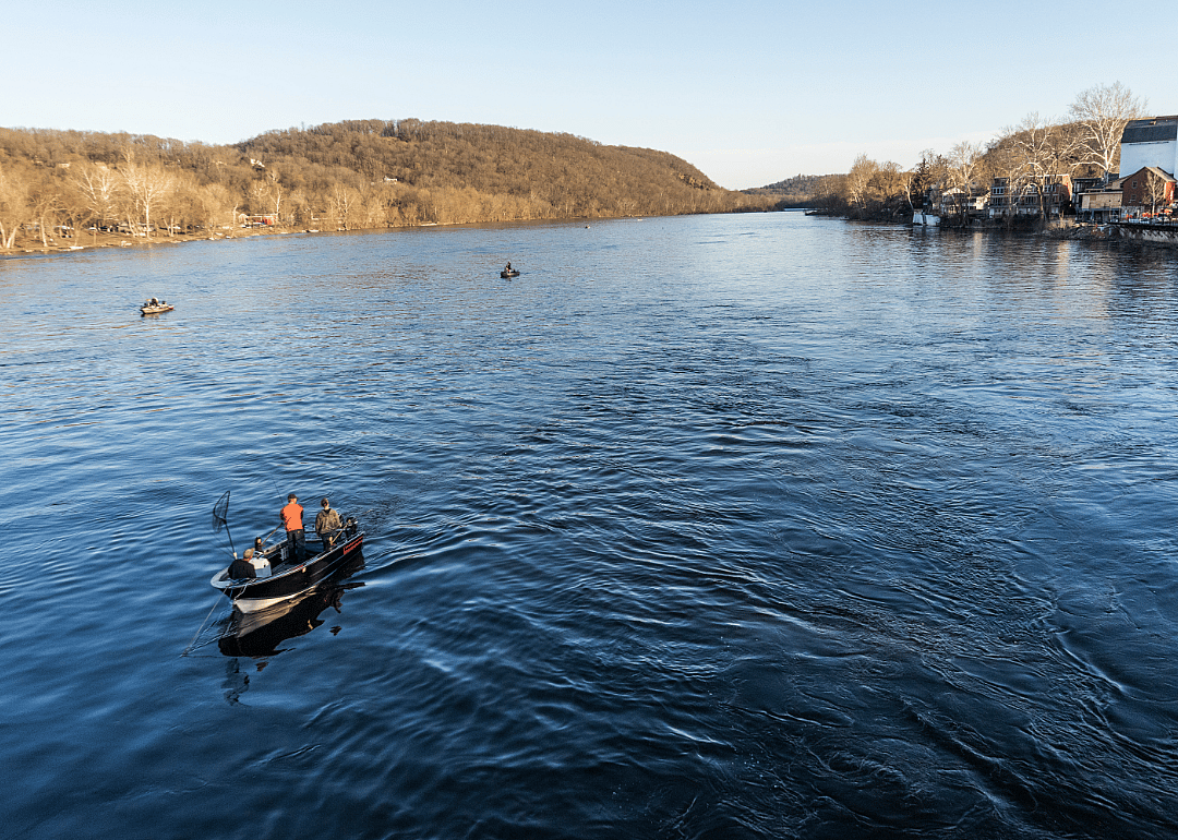 A few small boats make their way down a river. 