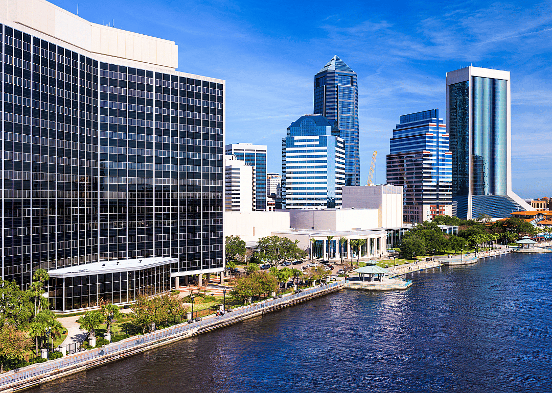A boardwalk along the water and the Jacksonville skyline.