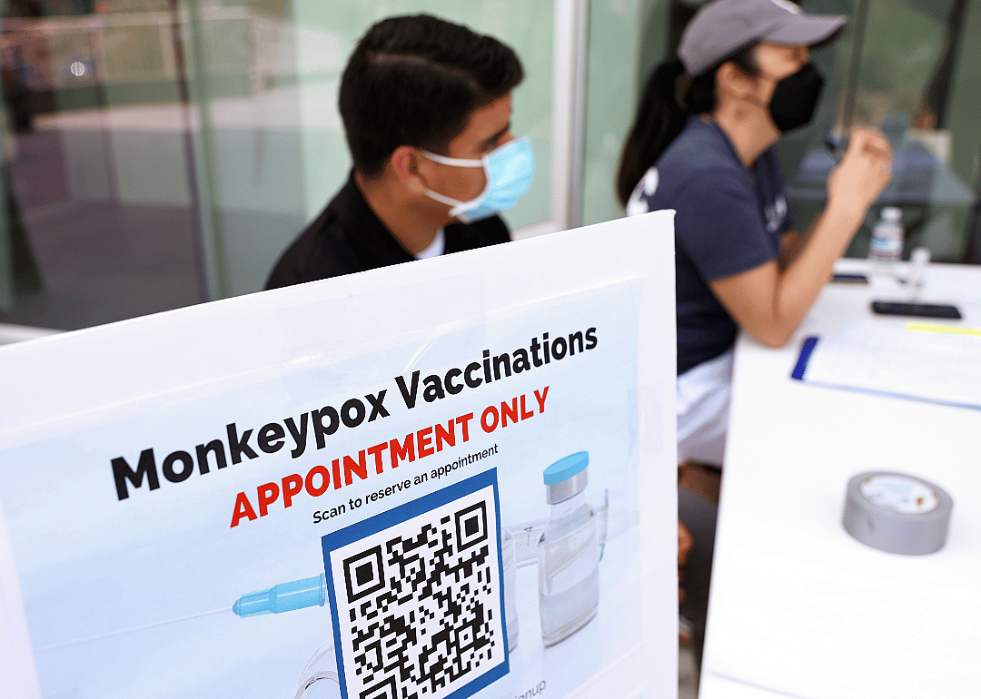 Health workers sitting at a check-in table at a pop-up Monkeypox vaccination clinic.