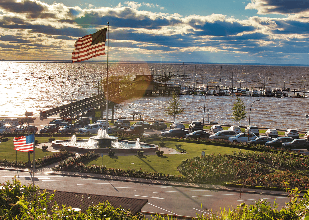 An American flag stands above a fountain on the edge of the ocean.