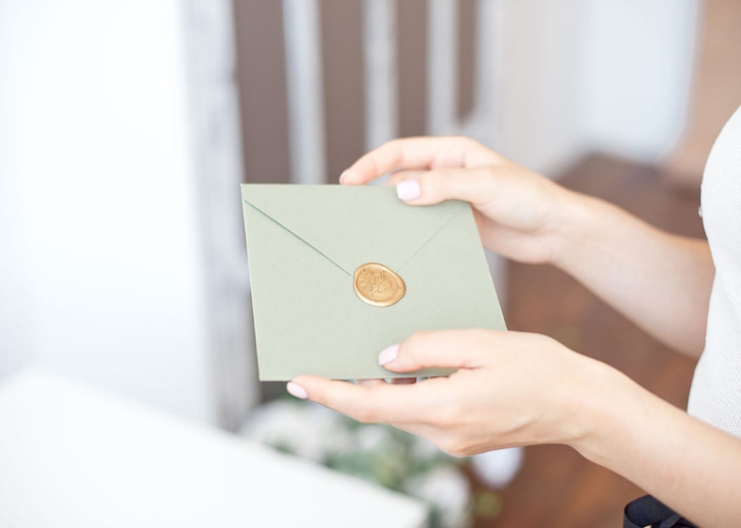 A woman holding a sealed card from the mail.