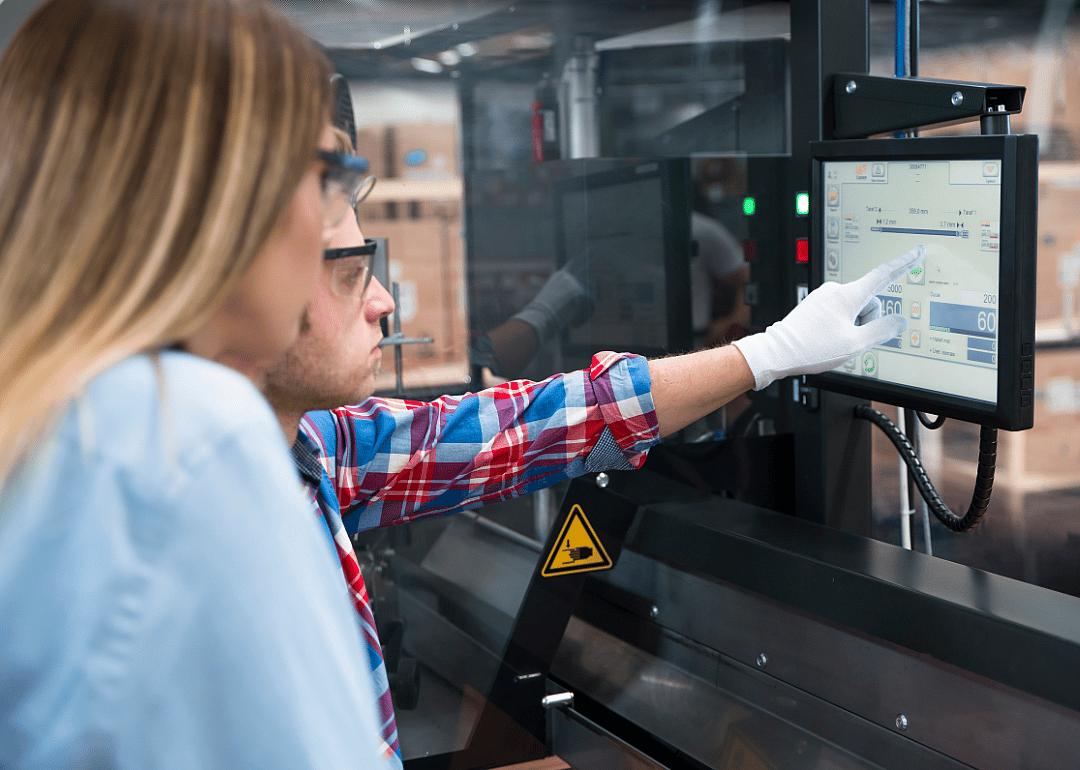 Two people analyzing numbers on a screen at a cable manufacturing plant.