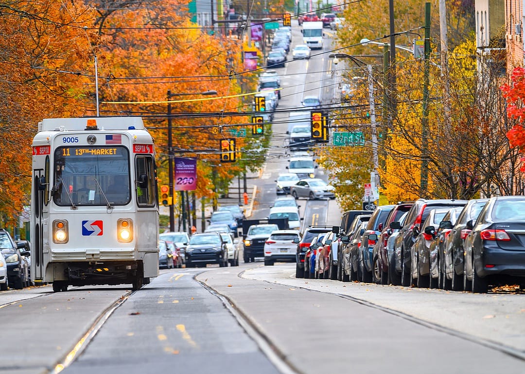 Fall trees lining a busy street with a trolley.