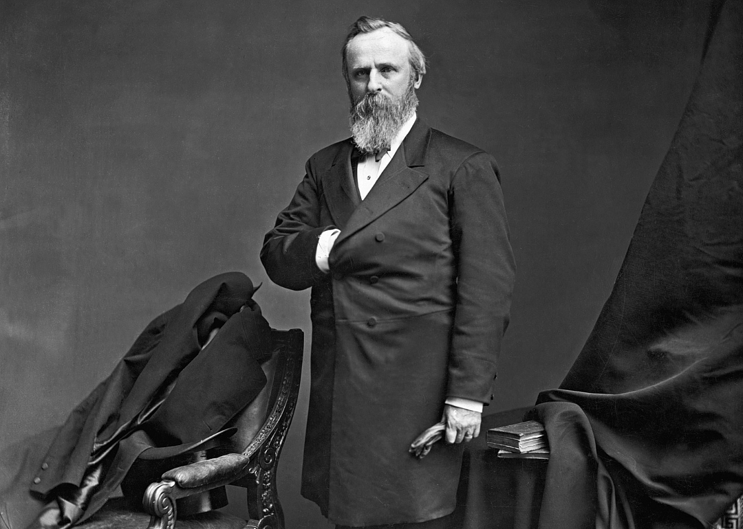 Rutherford B. Hayes posing for a portrait in a long dark suit jacket.