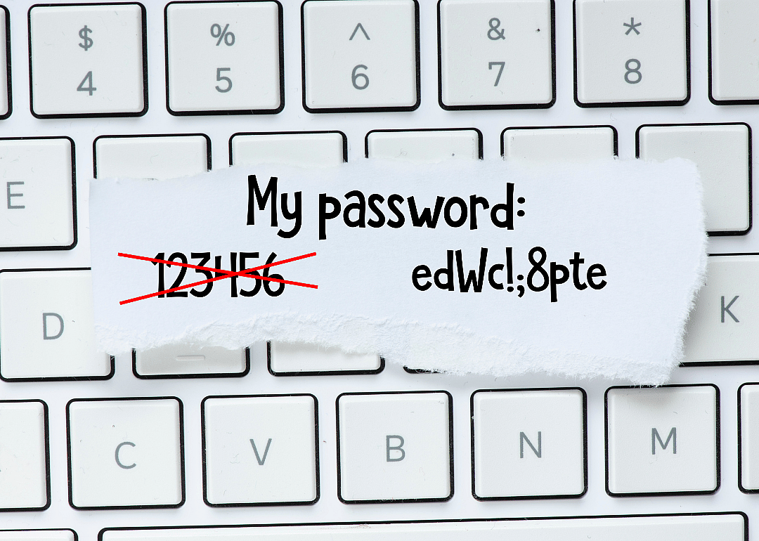 Scrap of paper with a crossed out password and a new one on top of a keyboard.