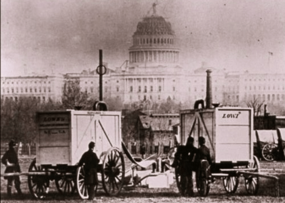 An old image of wagons and men in front of the Capitol in Washington.