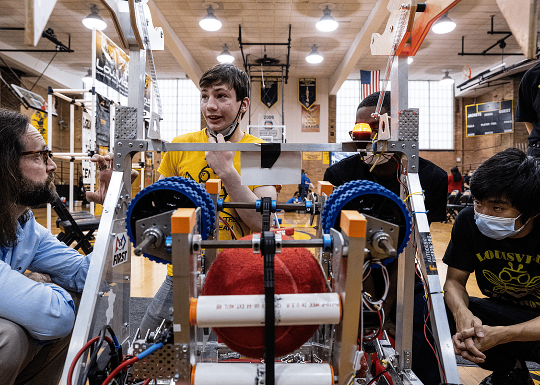 Members of the Central High School robotics club gather around a robot canine.
