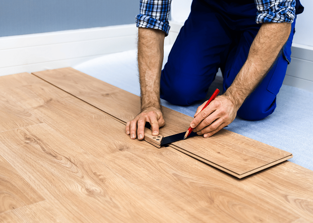 Person lining up and installing laminate flooring.