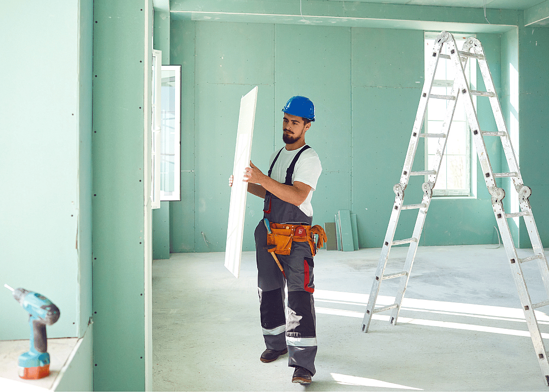Person carrying plasterboard to install.