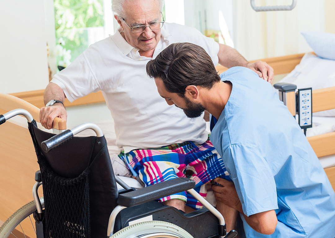 A nurse helping a patient out of a wheelchair.
