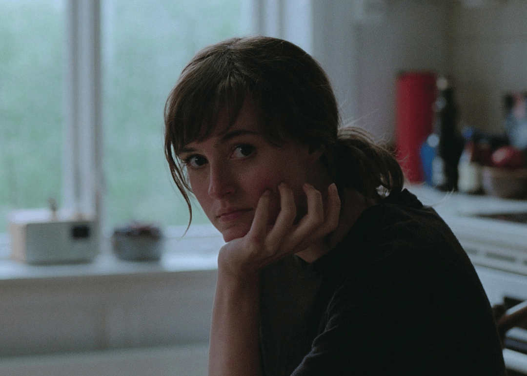 A young woman sits resting her head in her hand.