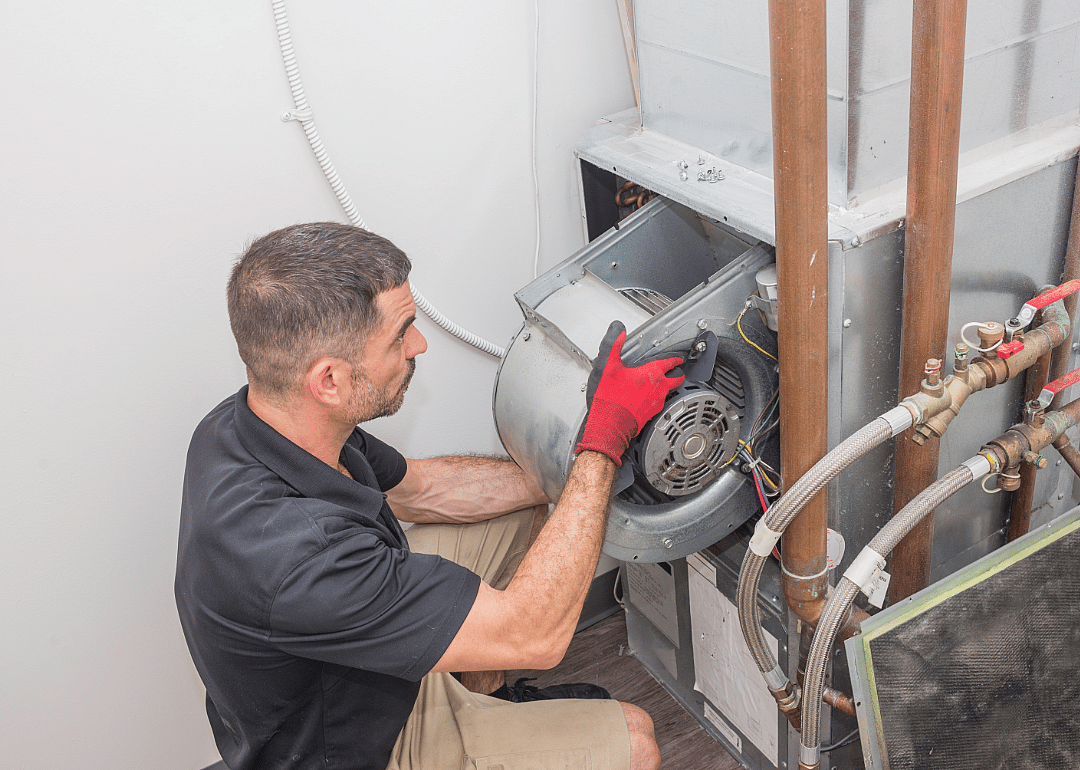A technician works on a furnace blower fan.