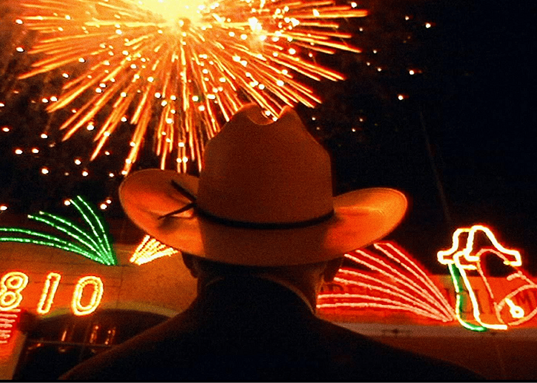 A man in a cowboy hat watching fireworks.