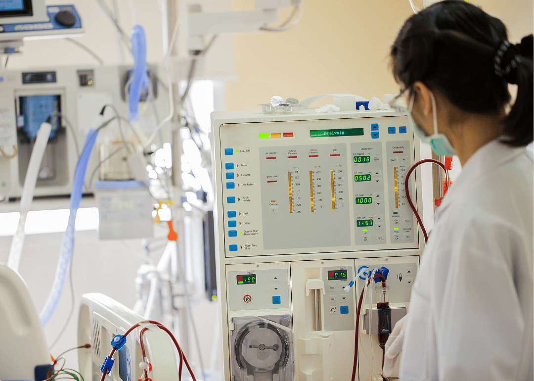 A medical professional presses buttons on a dialysis machine.