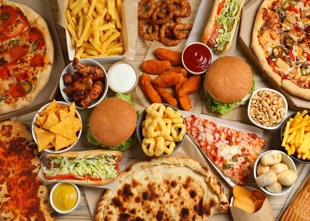An overhead view of various fast foods, including pizza, calzones, subs, chicken wings, burgers, and fries.