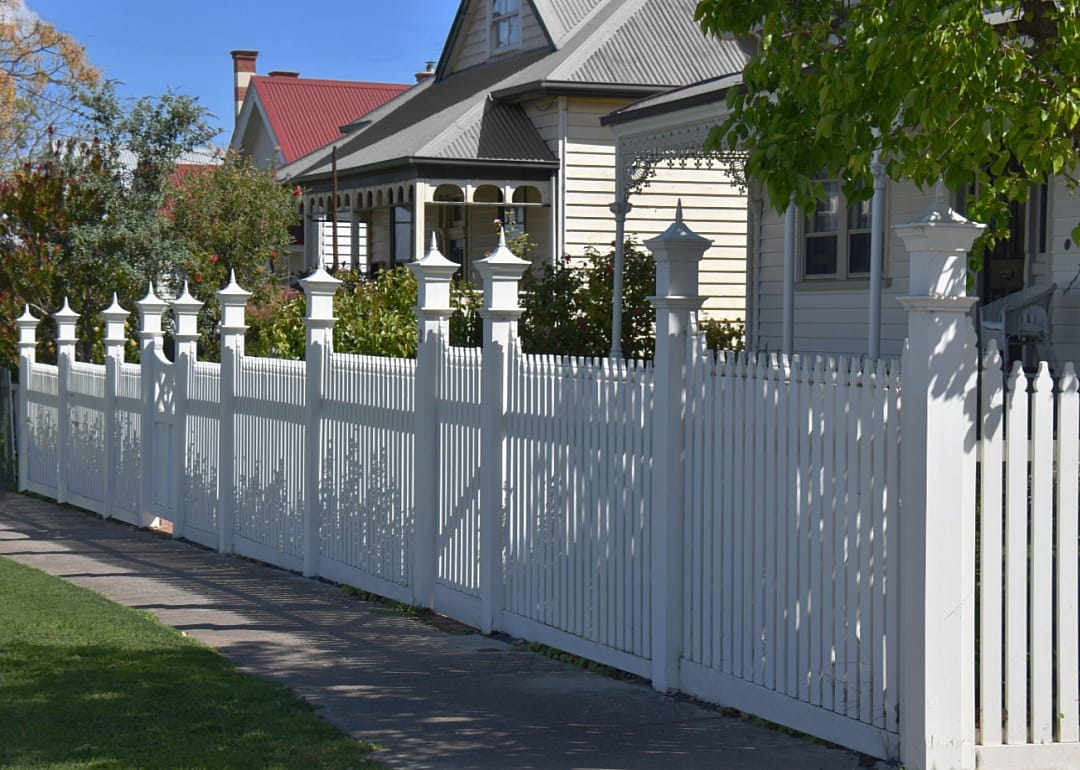Classic American homes lining the street with white fences.