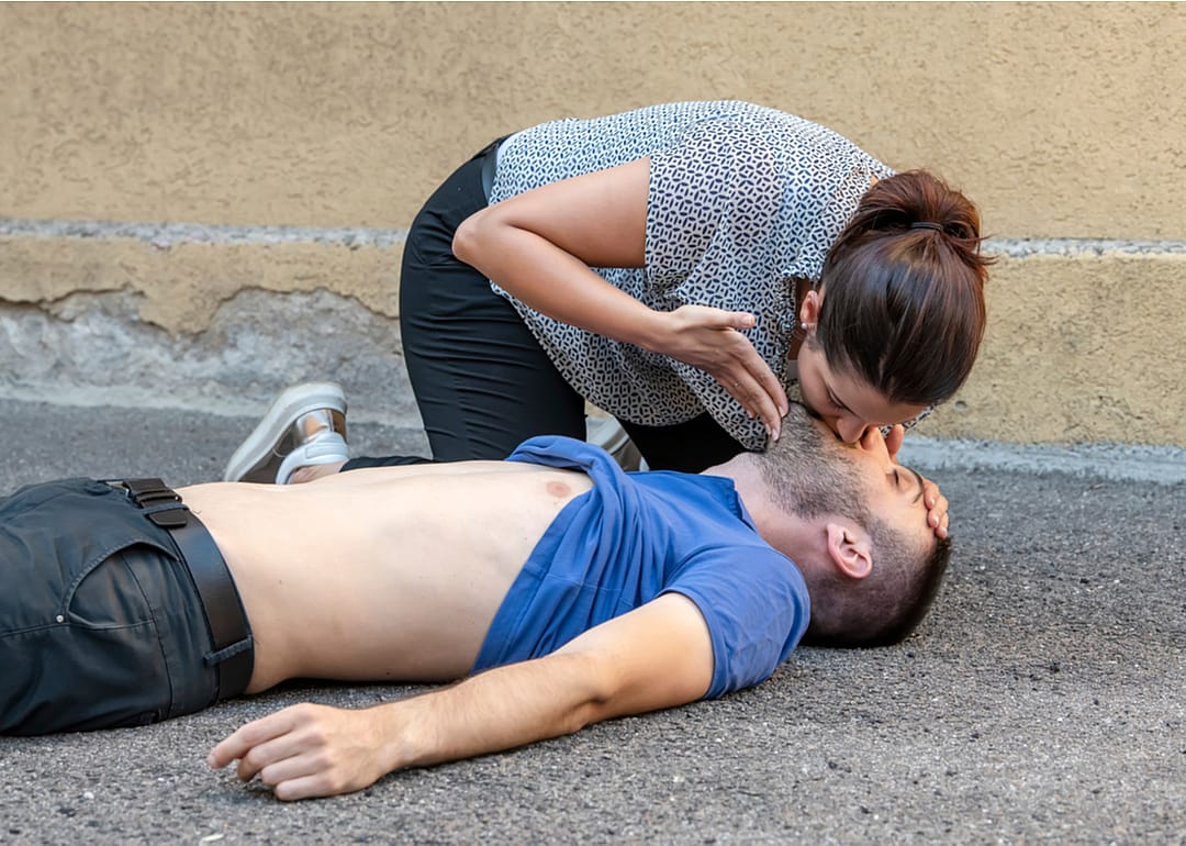 A woman performing mouth-to-mouth resuscitation on an unconscious man