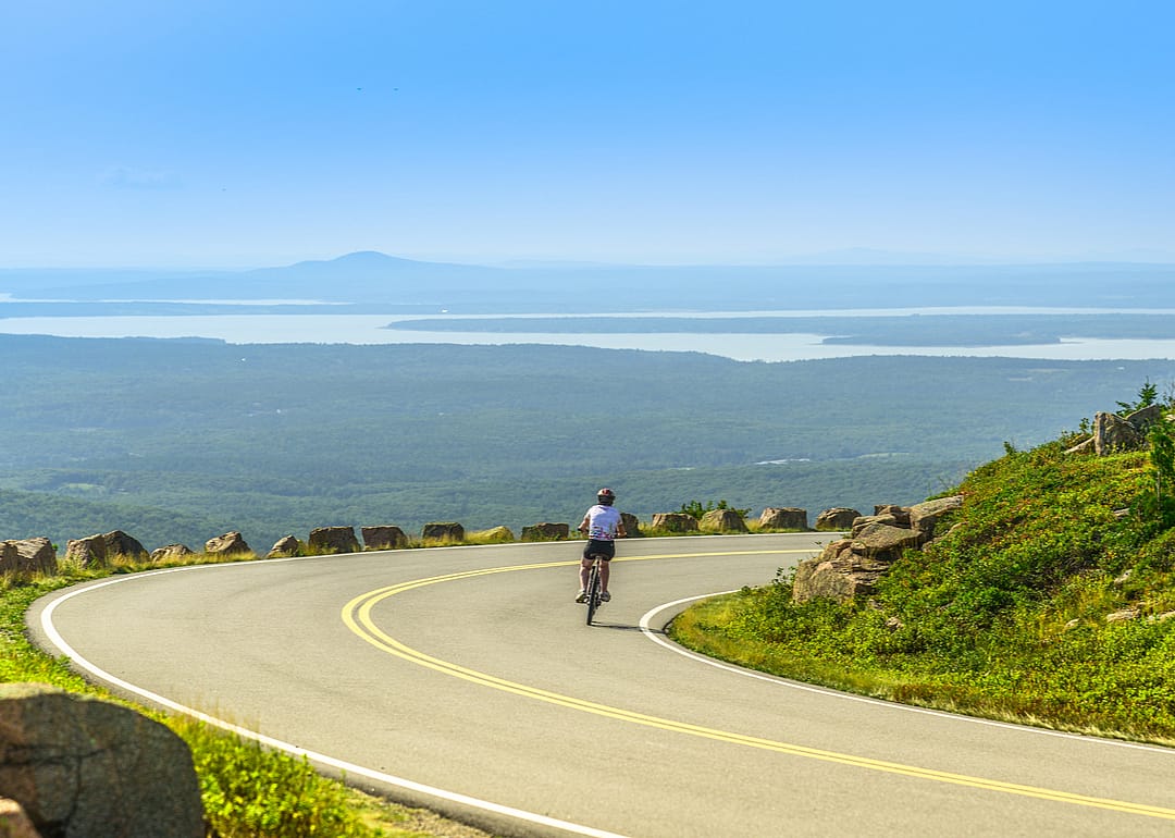 A bike cyclist riding downhill along Cadillac Mountain Road in Acadia National Park, Maine