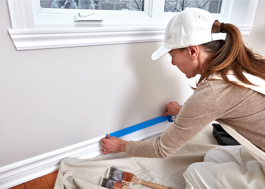 A woman painting a wall inside a home