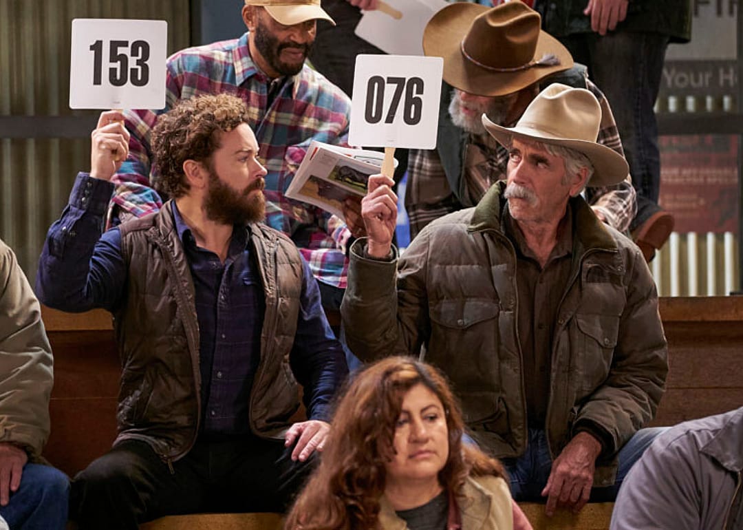 Danny Masterson and Sam Elliott holding up auction numbers.