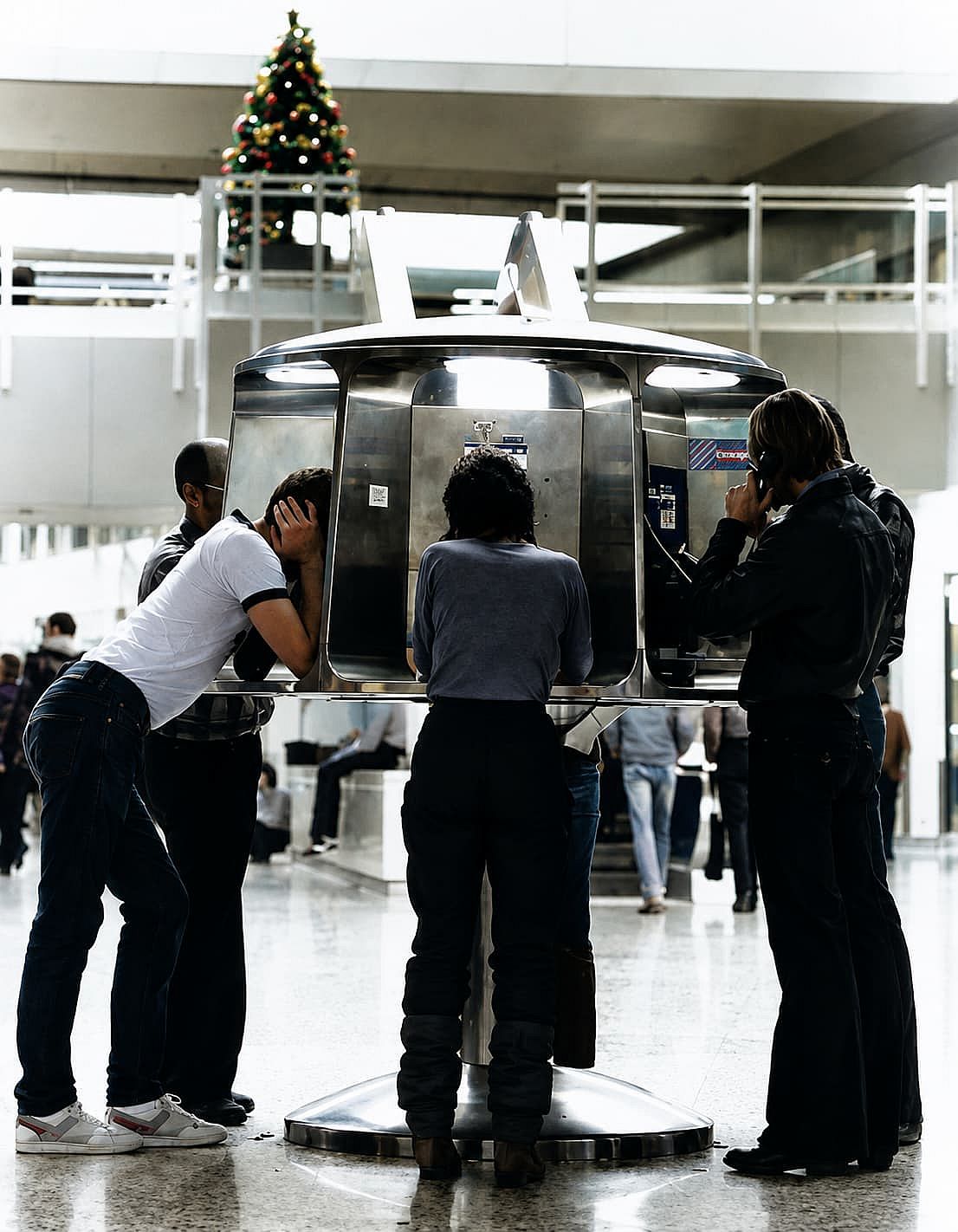 Different people talking on a payphone in Stapleton International Airport in 1982