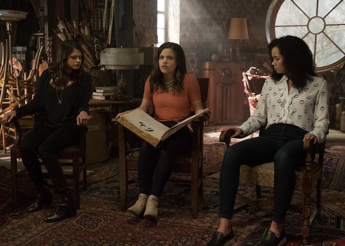 Three girls sit in chairs reading a spell.