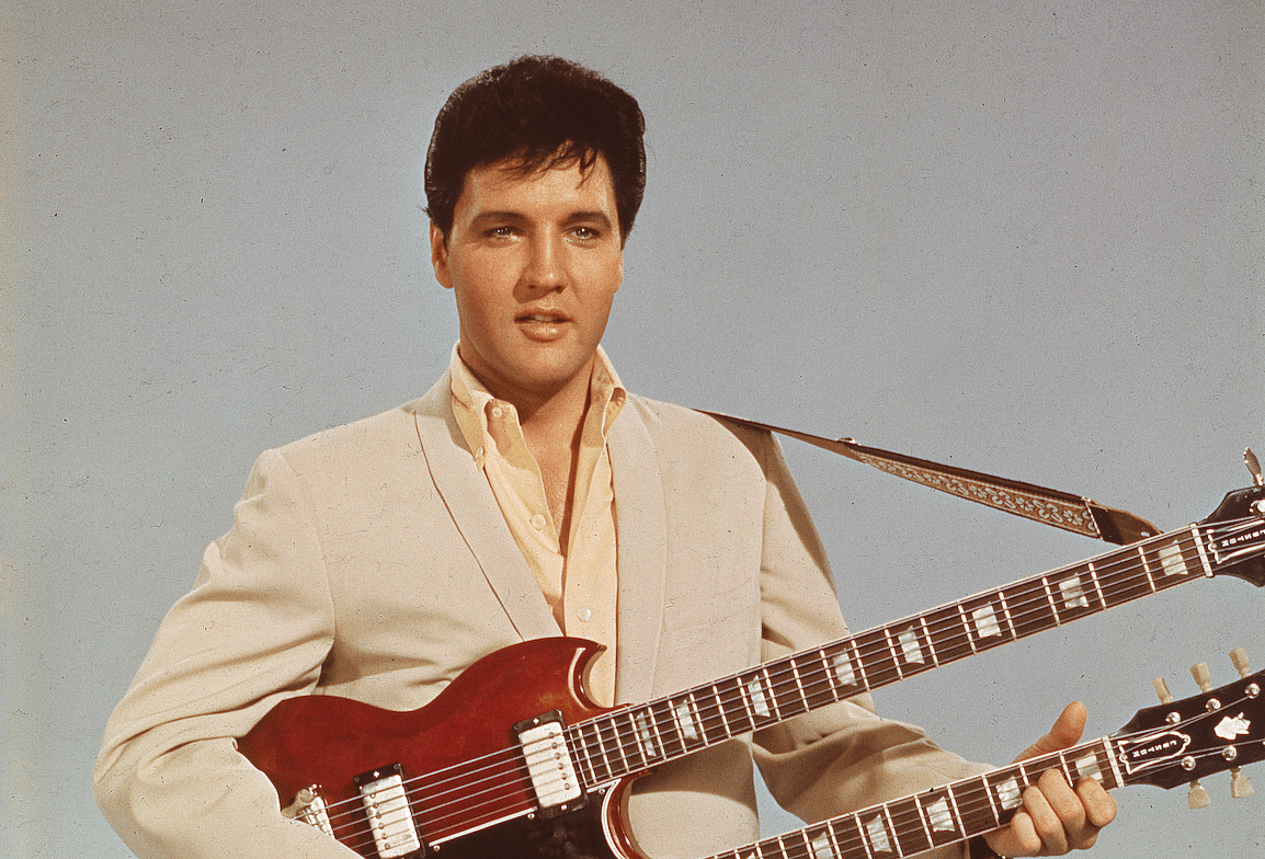 Elvis in a publicitiy still holding a guitar