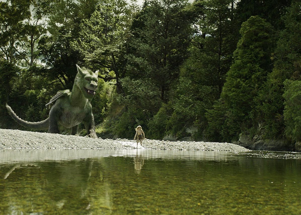 A boy and a giant green dragon on a rocky beach.