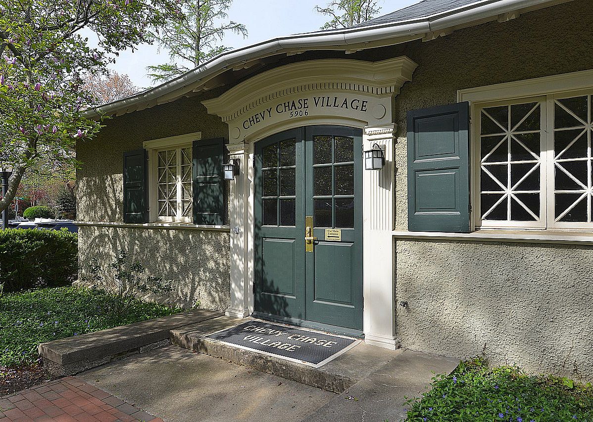 A small stone building with green trim reading Chevy Chase Village.