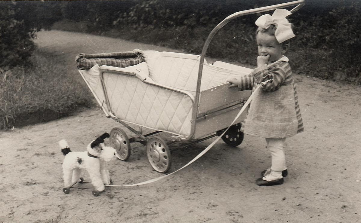 A small girl with dog toy and baby carriage, circa 1940
