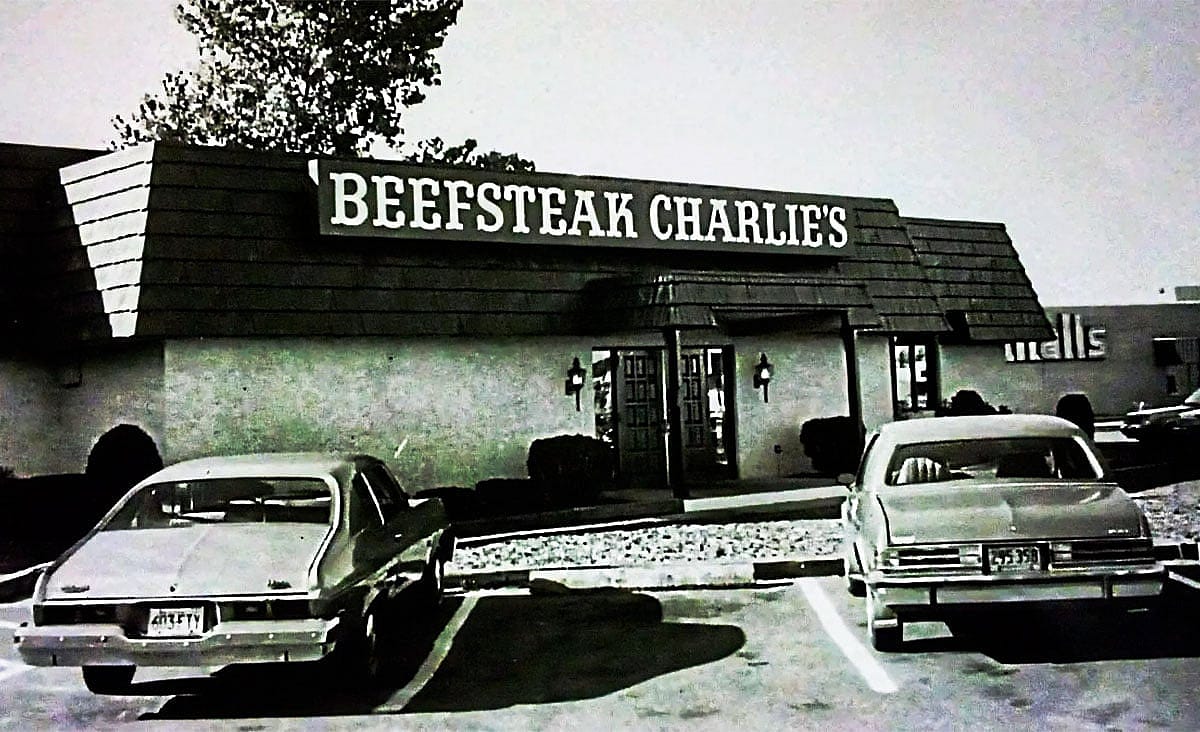 Vintage Beefsteak Charlie's restaurant exterior with parked cars in front of the building.