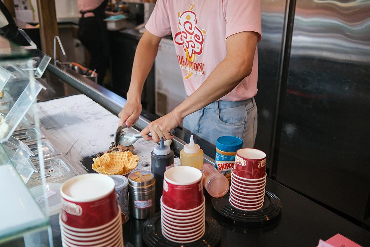 Cold Stone Creamery cups in multiple sizes with ice cream preparation going on behind them