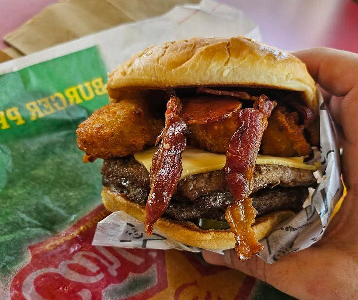 Hand holding an El Diablo Triple burger from Carl's Jr.