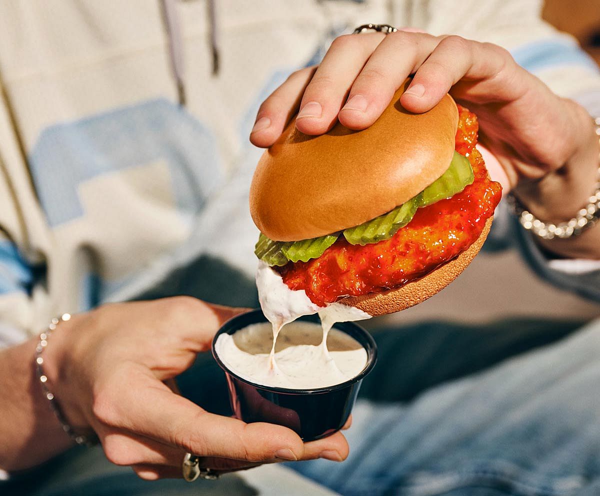 The Hot Honey Rub chicken sandwich from Wingstop being dipped into some ranch.