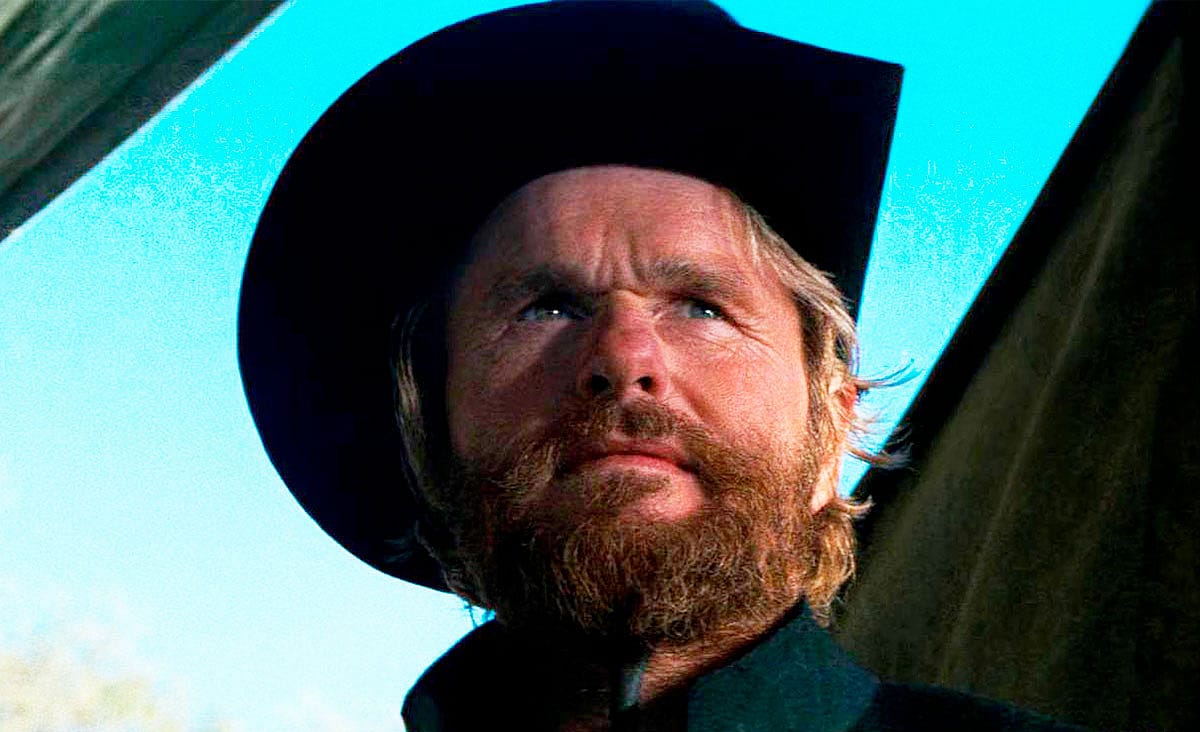 Clint Eastwood as Josey Wales in The Outlaw Josey Wales (1976), wearing a black cowboy hat and looking into the distance beneath a bright blue sky.