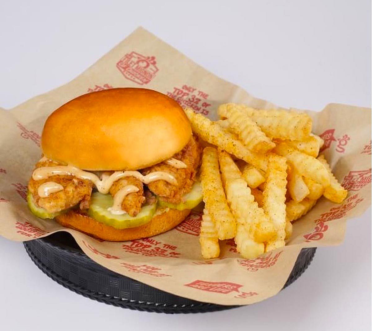 A chicken sandwich from Huey Magoo's and some french fries in a basket.