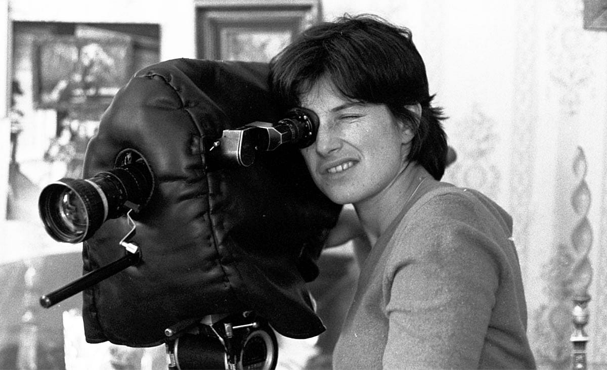 Chantal Akerman looks through the viewfinder of a film camera in a behind-the-scenes photograph from News from Home (1976).