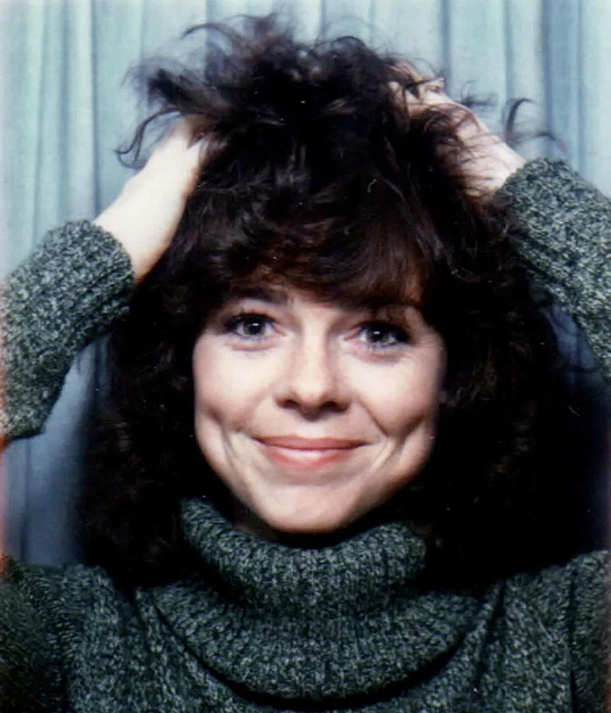Woman smiling and playing with her hair in a photo booth.