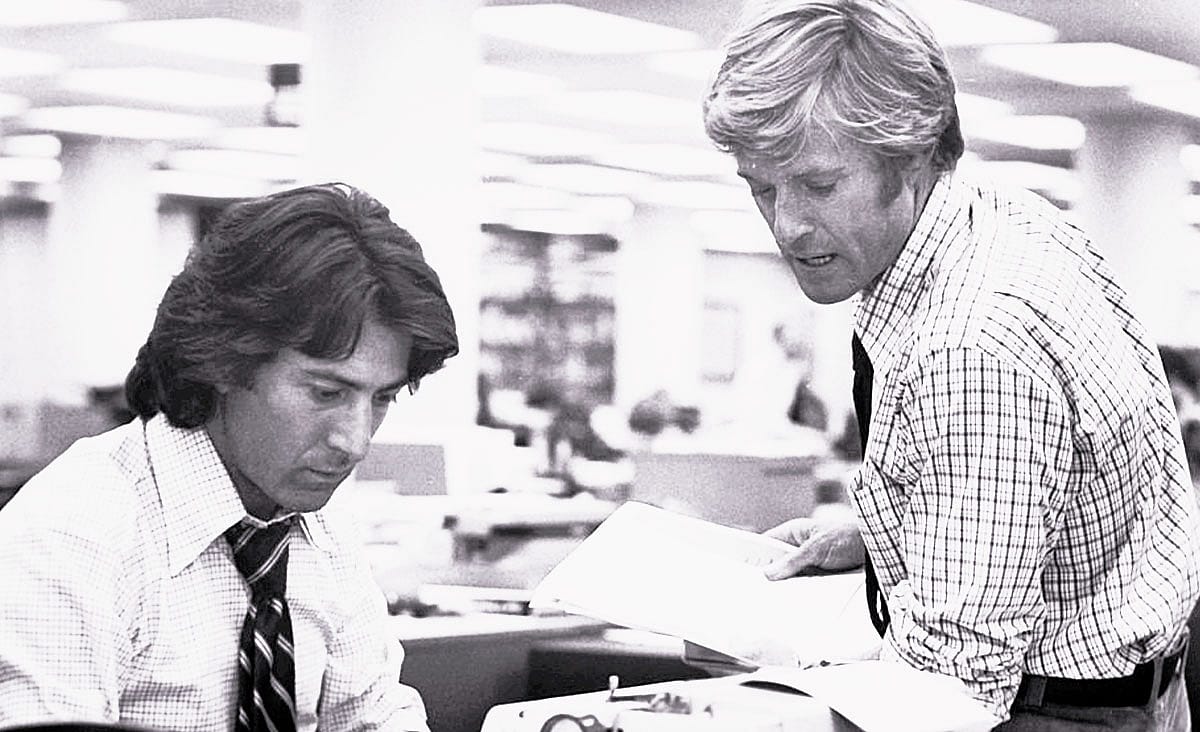 Austin Stoker and Laurie Zimmer in Assault on Precinct 13 (1976), standing together inside a police station, with Stoker wearing a sheriff's uniform and Zimmer dressed in a turtleneck sweater.