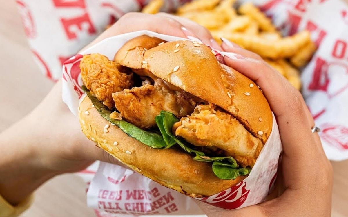 Hands holding a chicken sandwich from Raising Cane's