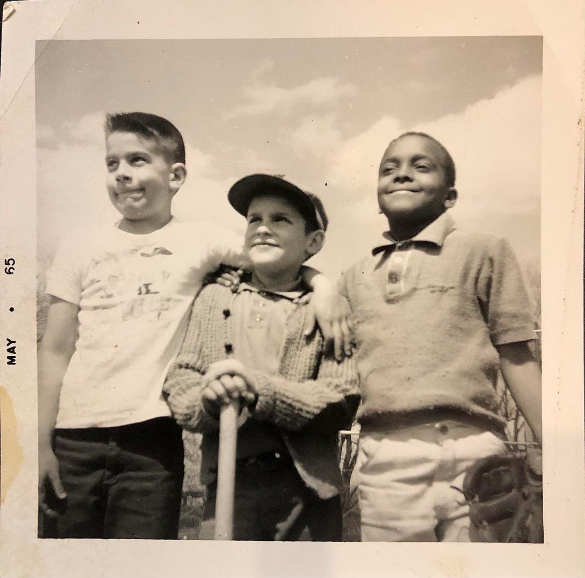 Three kids pose for a phot with a baseball bat and baseball glove.