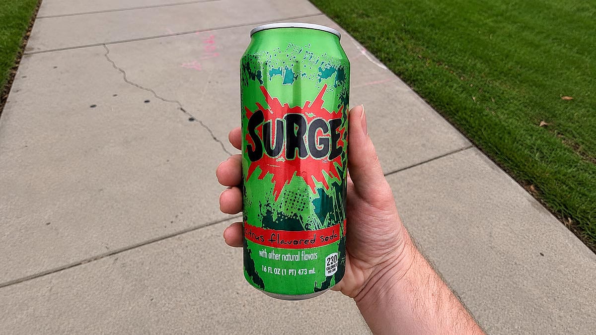 Surge soda can being enjoyed by someone outdoors.