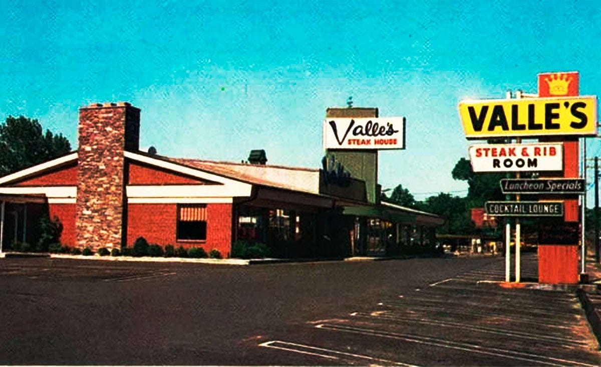 Exterior of a Valle's Steak House restaurant with a large roadside sign advertising steak and ribs, beside an empty parking lot.