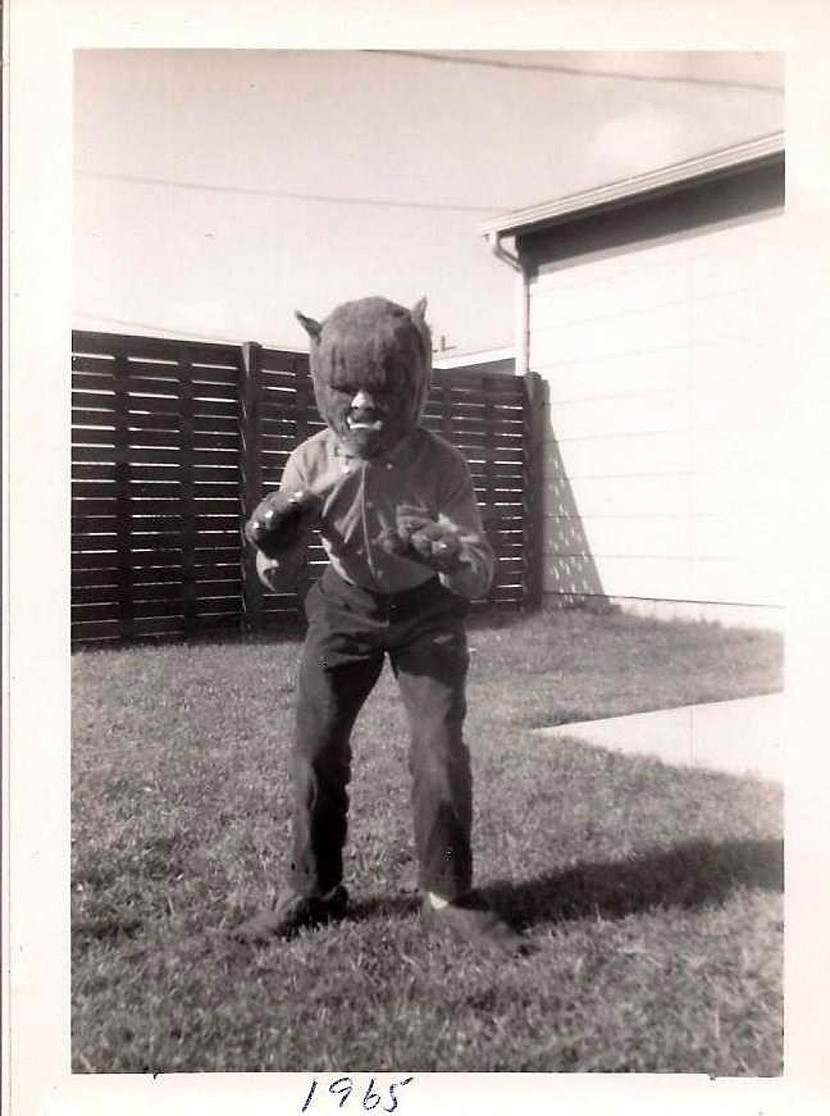 Black and white photo of a kid in his backyard dressed up as Wolfman 